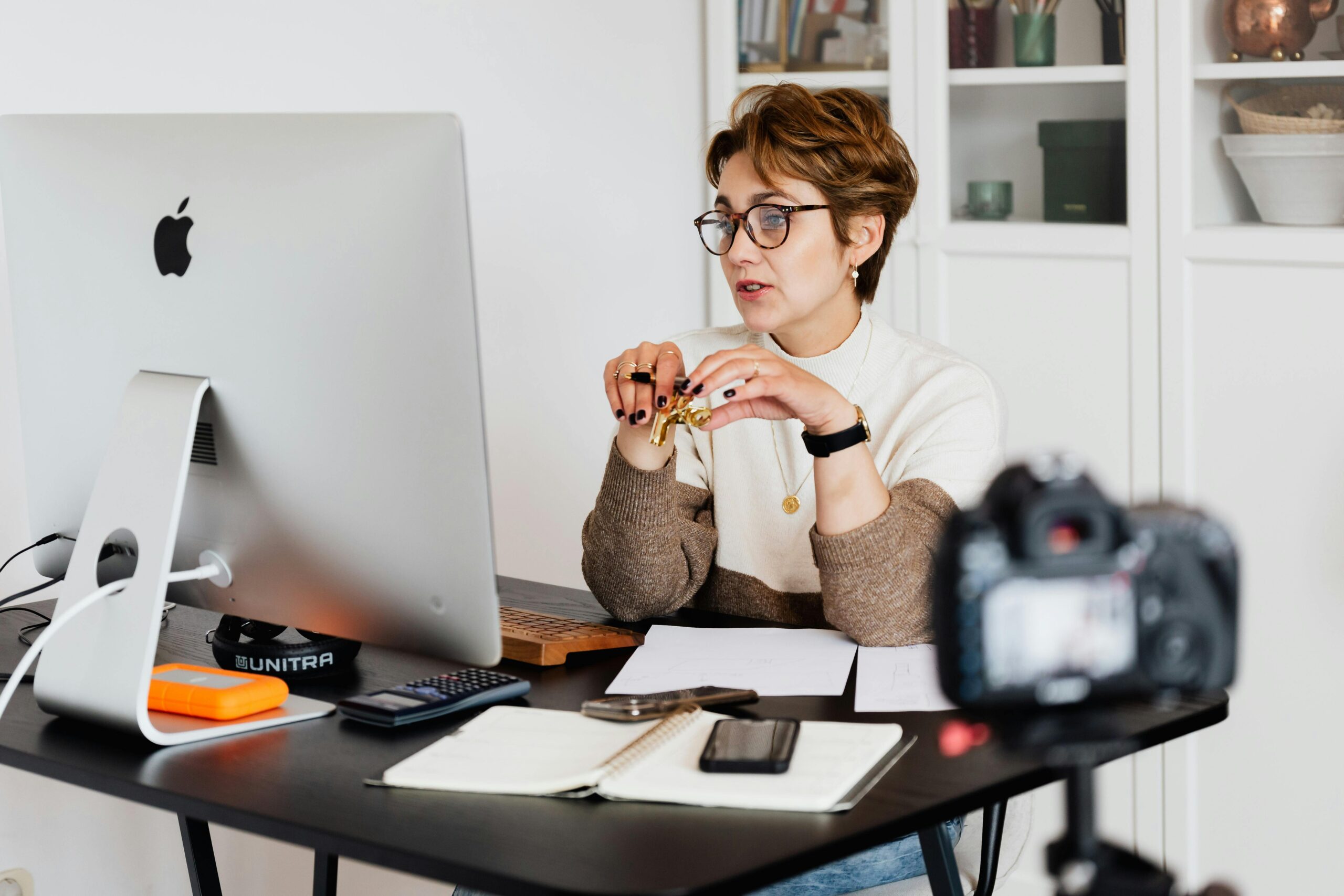 Online A Level Physics Tutor 1 A professional woman engaged in a virtual meeting setup at her home desk, using a computer and camera.